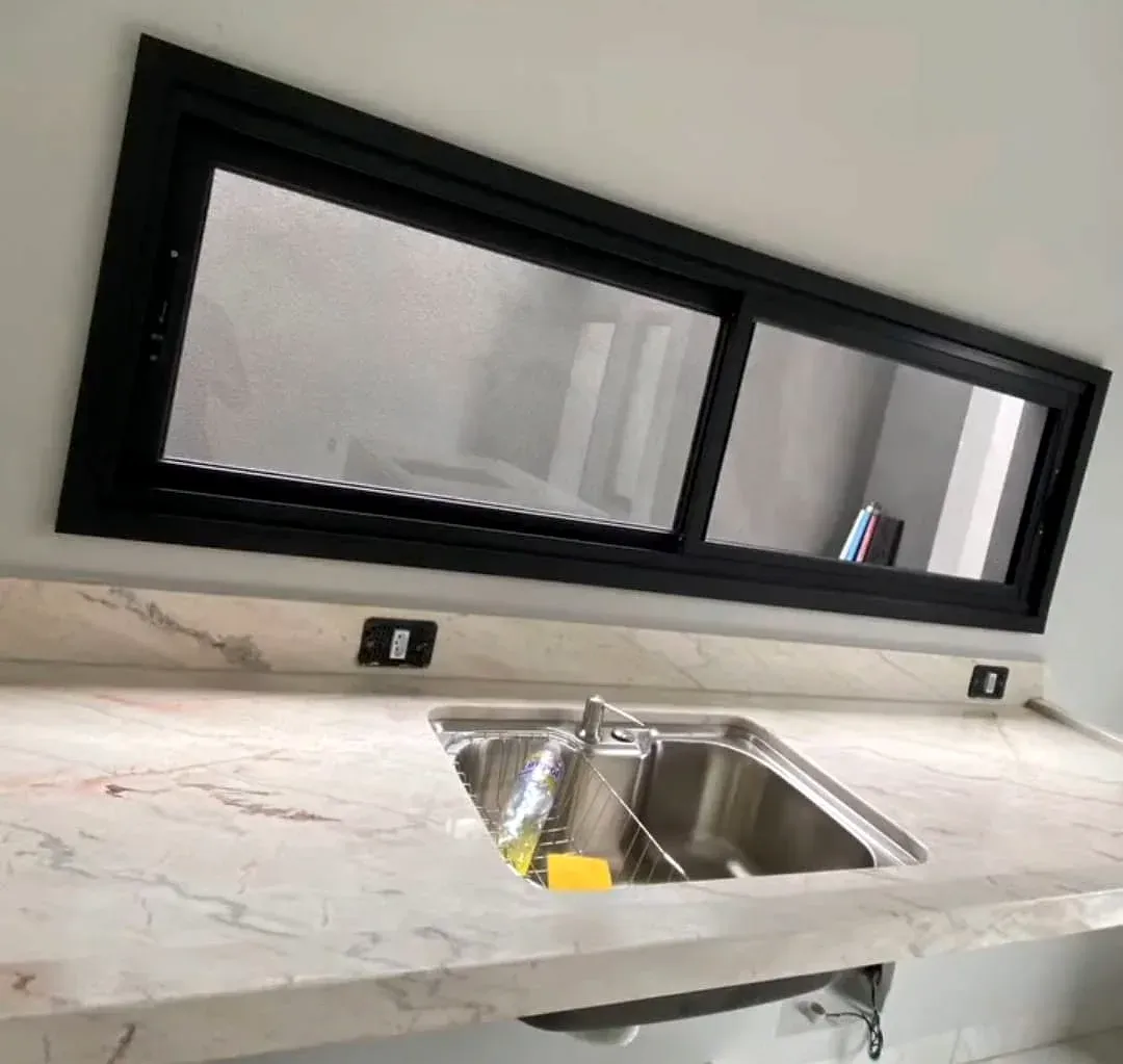 Janela de correr em esquadria de alumínio preto sobre bancada de cozinha