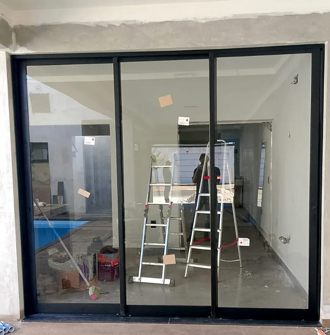 Porta de correr em esquadria de alumínio preto com vidro, em obra com vista para a piscina