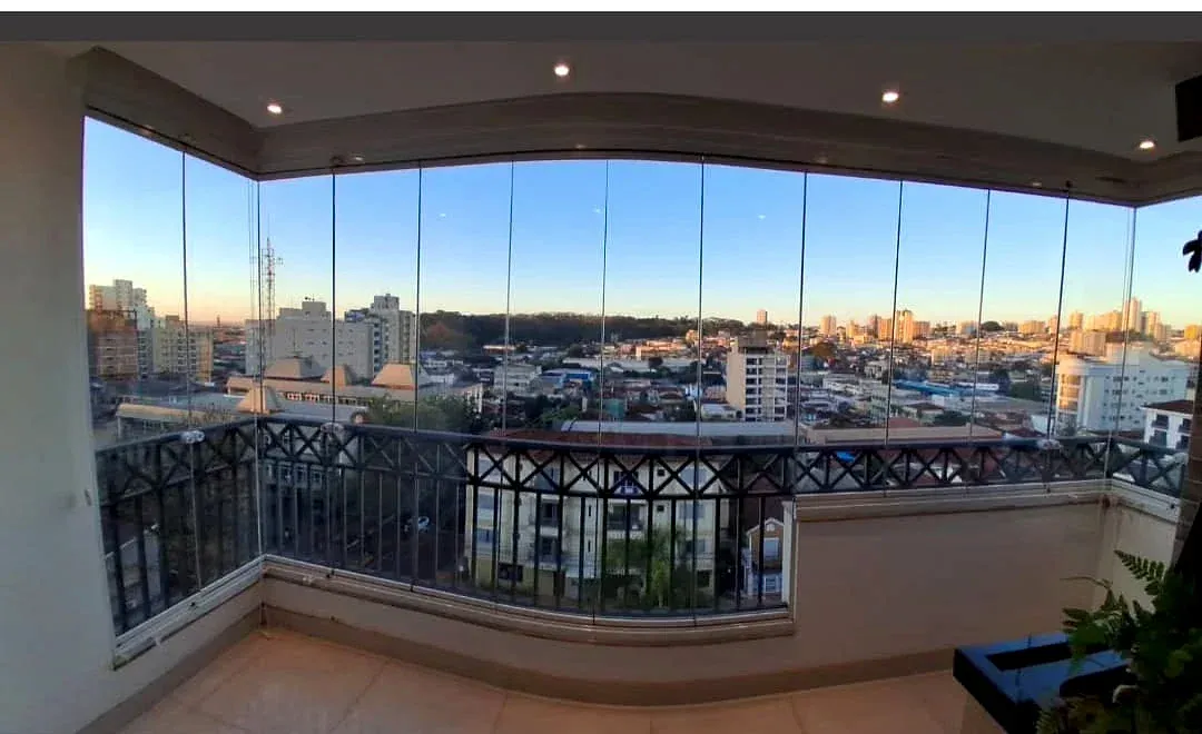 Sacada envidraçada com vista para a cidade ao entardecer
